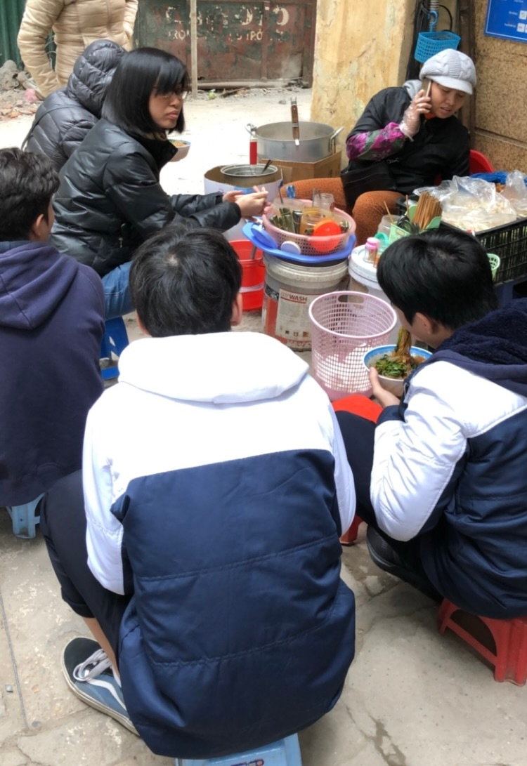 Locals gathering around to eat street food in Hanoi