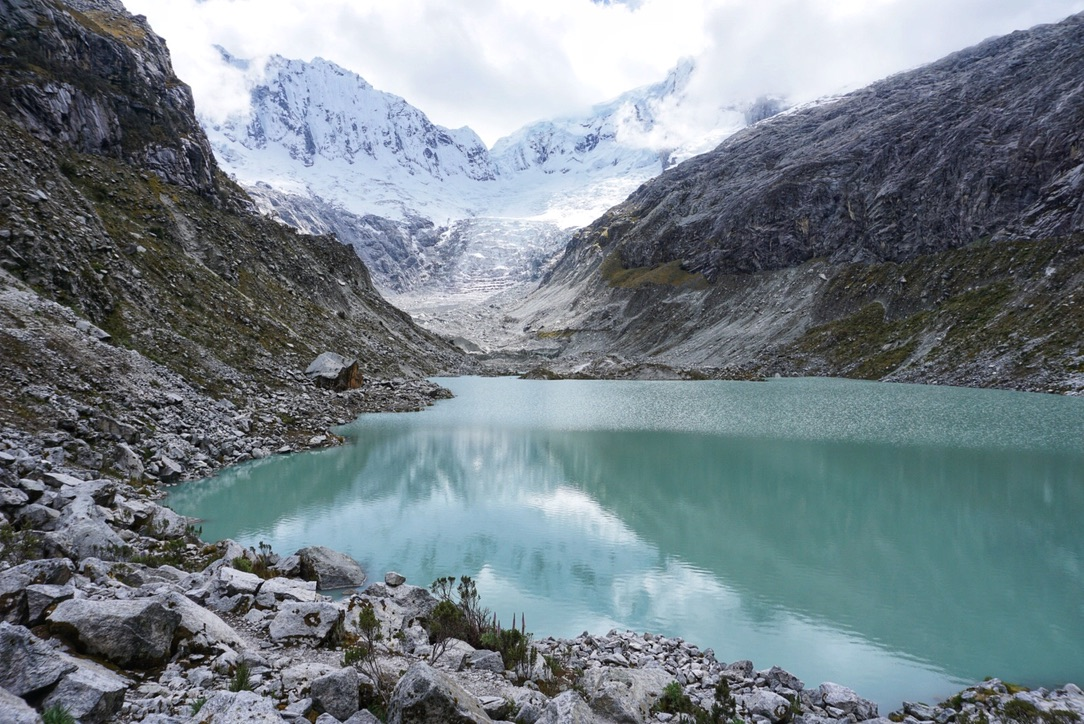 The lake is surrounding by mountains and a glacier at the back.