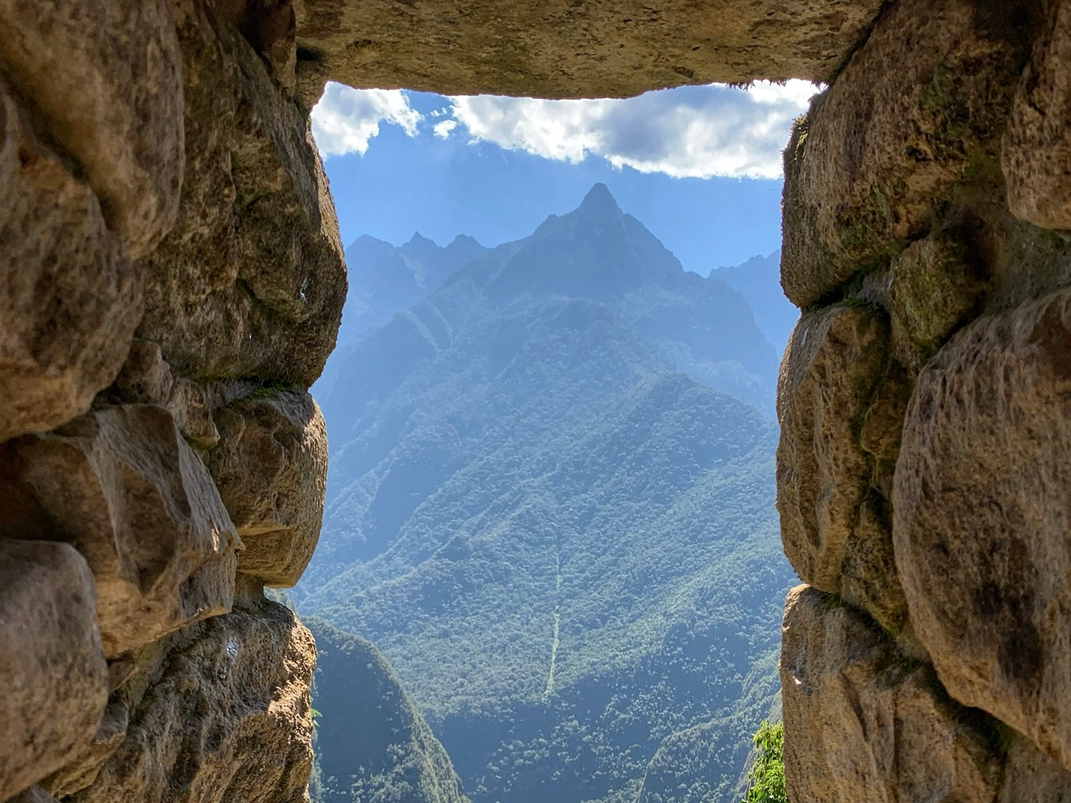 A view of the distant mountains viewed through a stone window at Machu Picchu